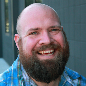A headshot of J.R. Top, a man with friendly eyes and a good beard.